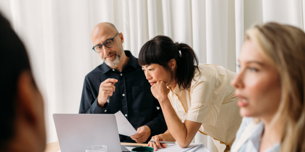 Business and technology professionals collaborating around a laptop